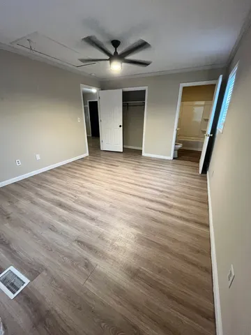 a view of an empty room with wooden floor and a window
