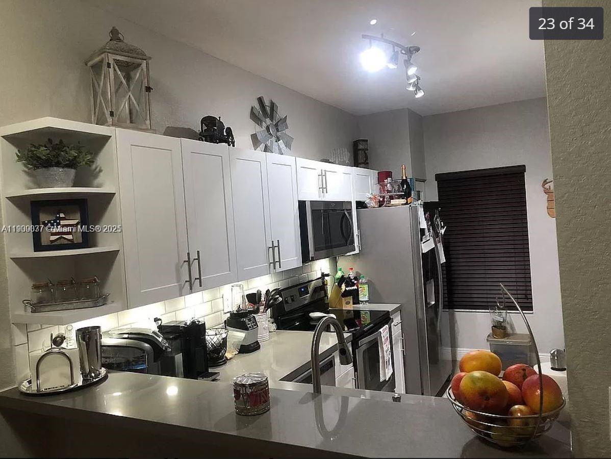 4913 Southwest 141st Avenue, Unit 2 Miramar, FL 33027 - Photo 1 of 12 a kitchen with a sink a stove and chairs