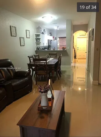 a living room with a table chairs and a refrigerator