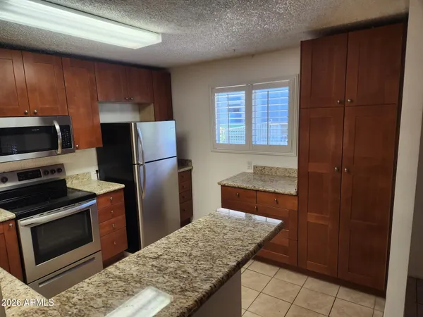 a kitchen with granite countertop a refrigerator stove and sink