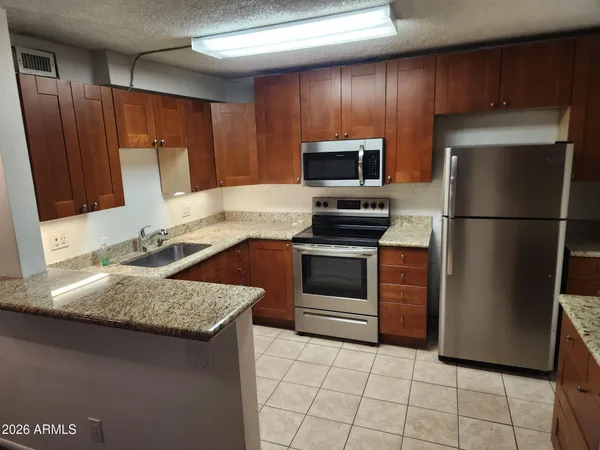 a kitchen with granite countertop a refrigerator and a sink
