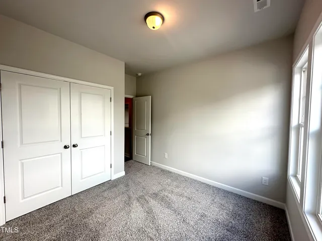 an empty room with closet area and natural light