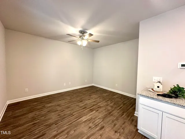 an empty room with wooden floor and chandelier fan