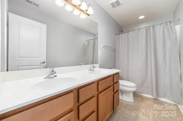 a bathroom with a double vanity sink toilet and a mirror