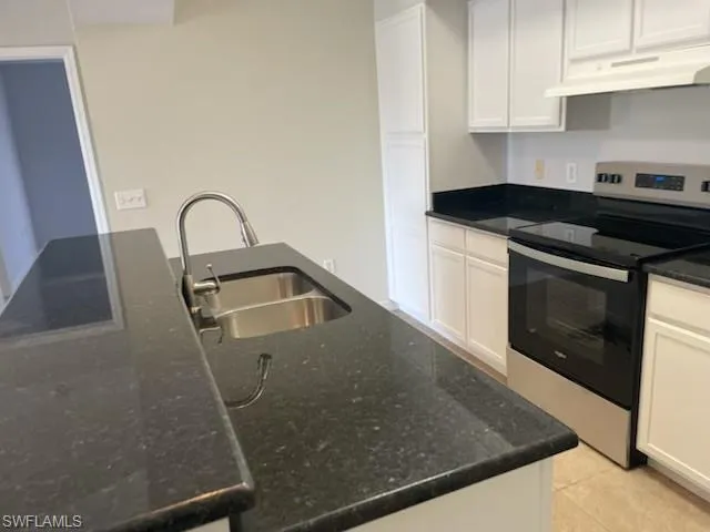 a kitchen with granite countertop a sink a stove and cabinets