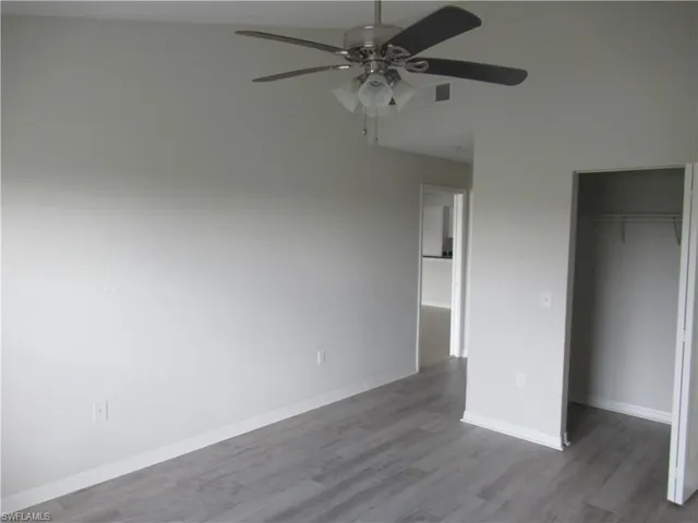 an empty room with wooden floor and fan