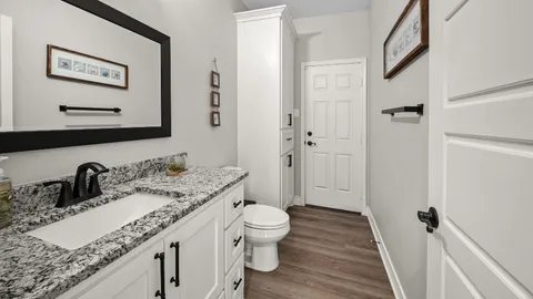 a bathroom with a granite countertop sink a toilet and a large mirror