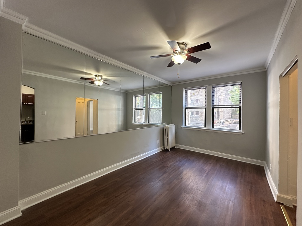 661 West Sheridan Road, Unit 208 Chicago, IL 60613 - Photo 7 of 20 a view of an empty room with wooden floor and a window