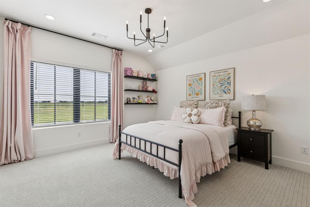 1890 McConnell Road Gunter, TX 75058 - Photo 33 of 40 a spacious bedroom with a large bed and a chandelier