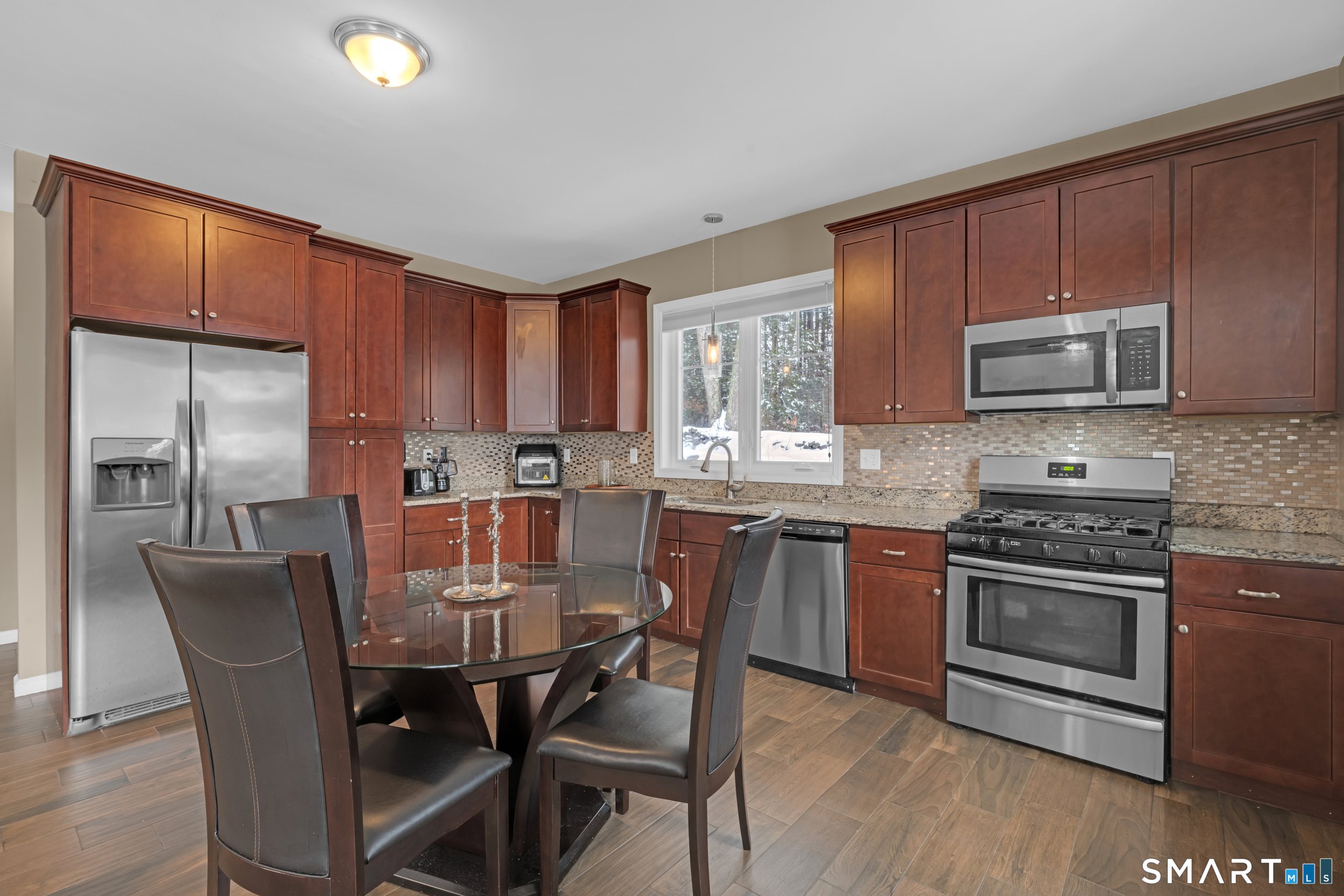 123 Ashford Road, Unit 1 Eastford, CT 06242 - Photo 4 of 23 a kitchen with stainless steel appliances wooden cabinets granite counter tops a stove a dining table and chairs