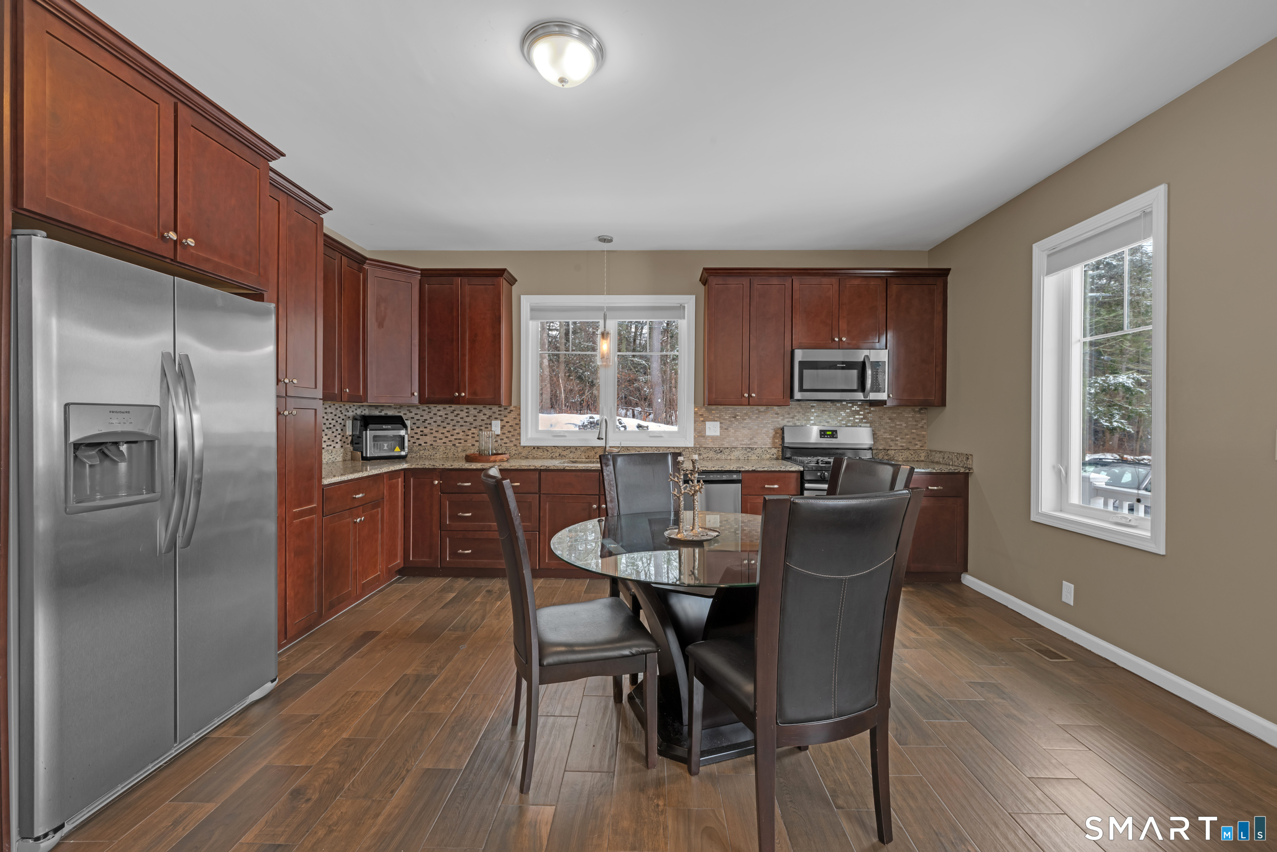 123 Ashford Road, Unit 1 Eastford, CT 06242 - Photo 7 of 23 a kitchen with stainless steel appliances granite countertop a refrigerator a stove a sink dishwasher and a dining table with wooden floor