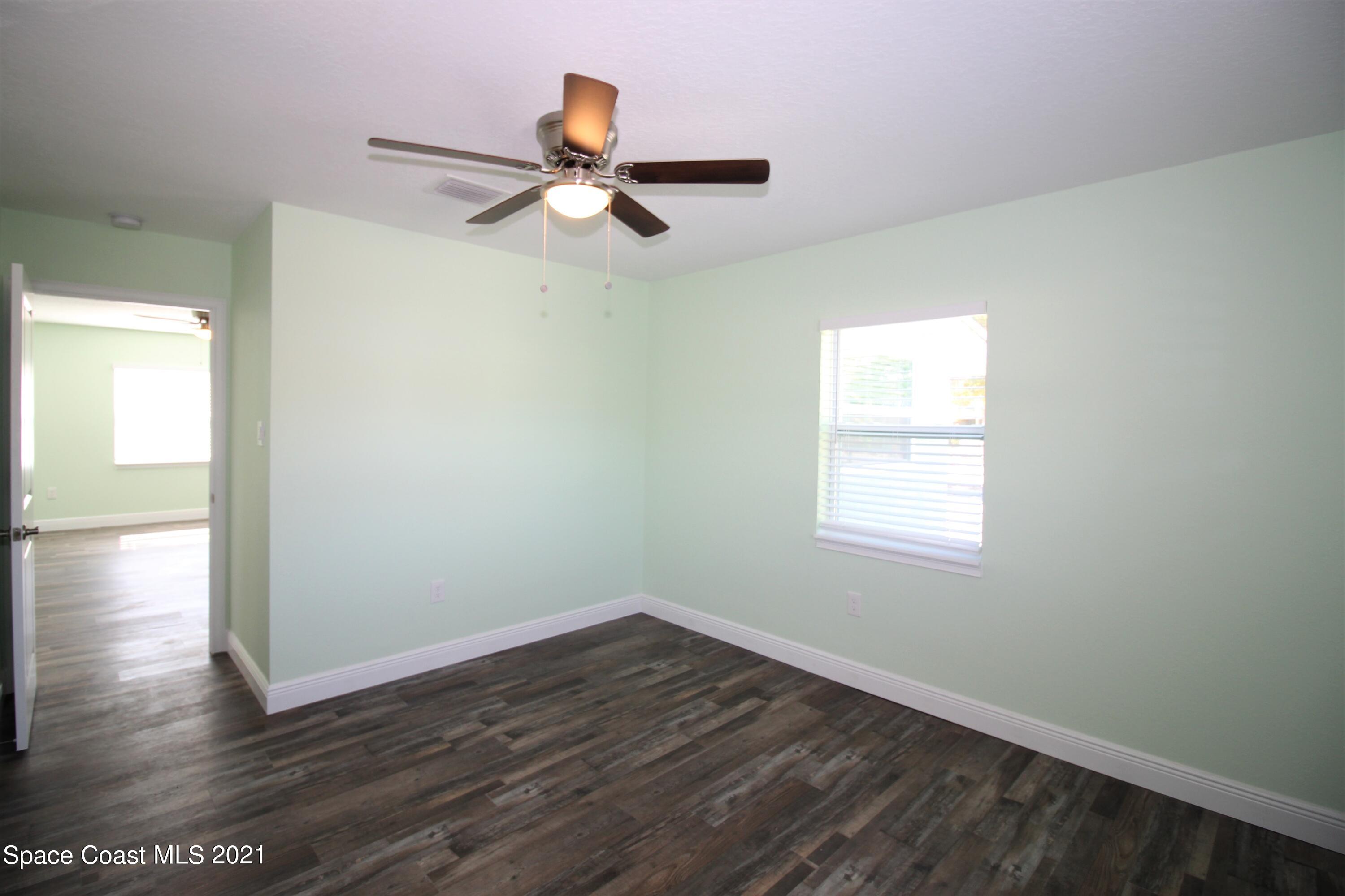 244 North Grove Street Merritt Island, FL 32953 - Photo 12 of 25 an empty room with wooden floor fan and windows