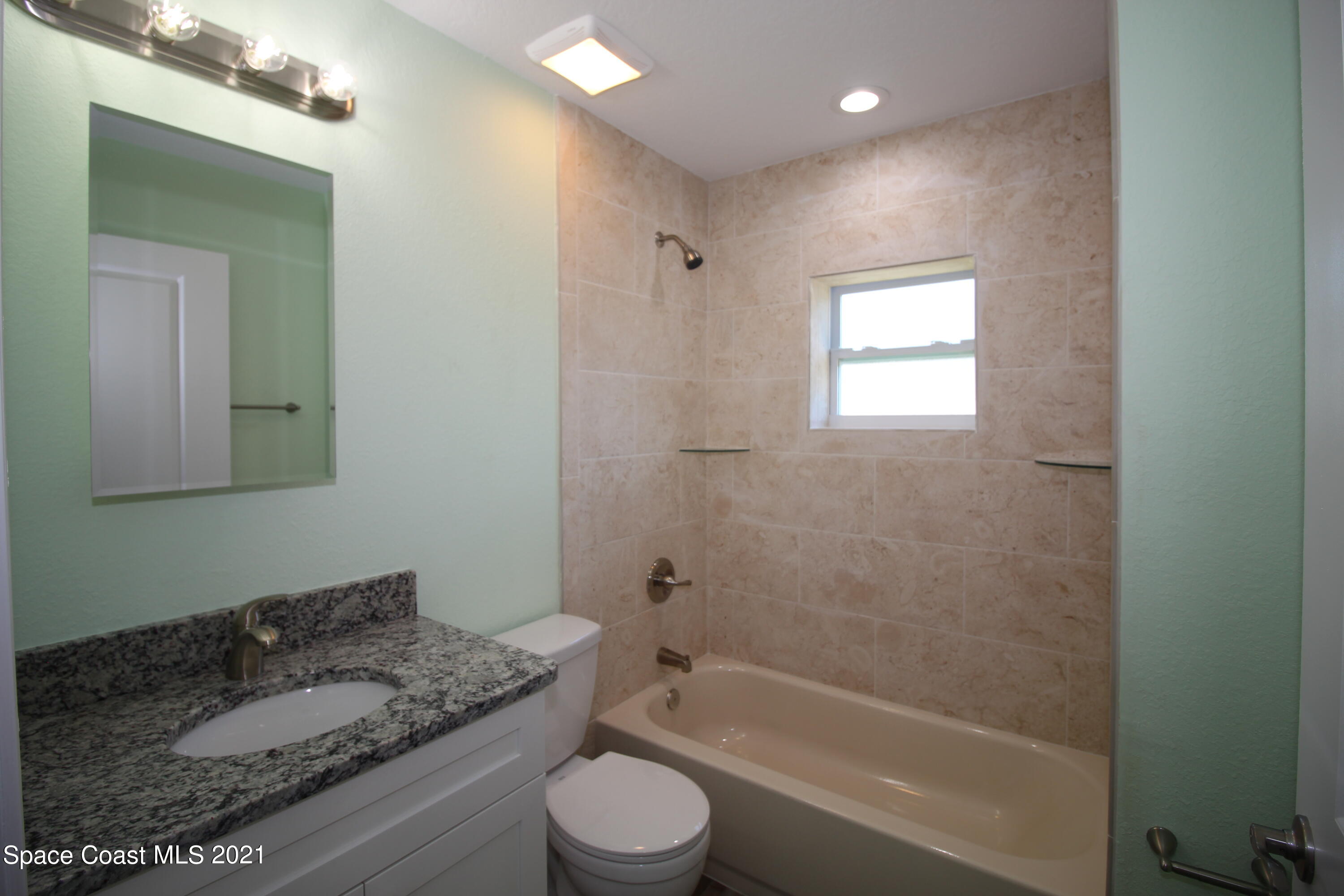 244 North Grove Street Merritt Island, FL 32953 - Photo 13 of 25 a bathroom with a granite countertop sink toilet mirror and bathtub