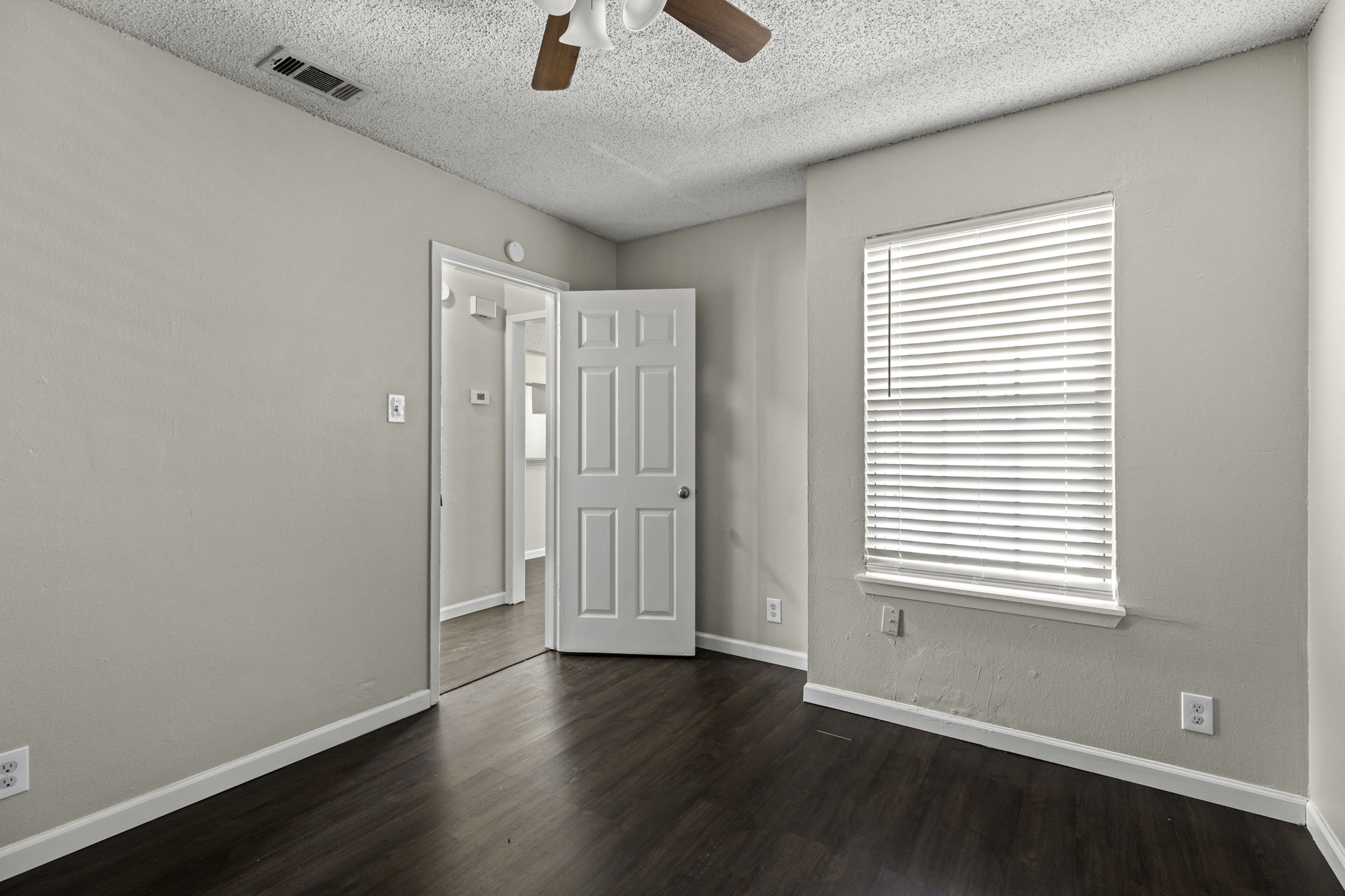 6110 Wheless Cove, Unit F Austin, TX 78723 - Photo 8 of 12 Unfurnished room featuring ceiling fan, dark wood-style flooring, and a textured ceiling