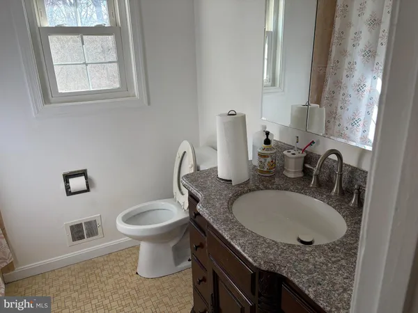 a bathroom with a granite countertop sink and a toilet