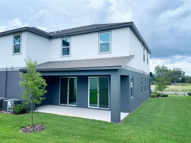 a view of a house with a yard potted plants and a table