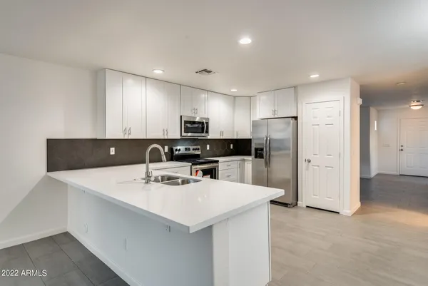 a kitchen with stainless steel appliances a refrigerator sink and white cabinets