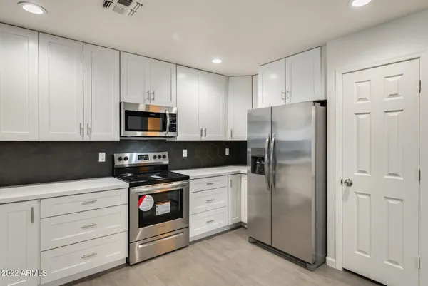 a kitchen with white cabinets and stainless steel appliances