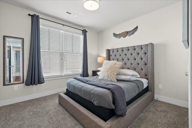 a large bed sitting in a bedroom next to a window and a lamp