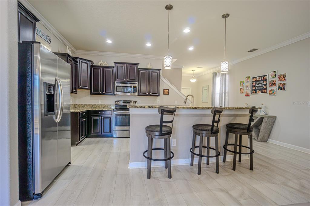 1762 Hadden Hall Place Trinity, FL 34655 - Photo 17 of 39 a kitchen with stainless steel appliances a dining table chairs refrigerator and microwave