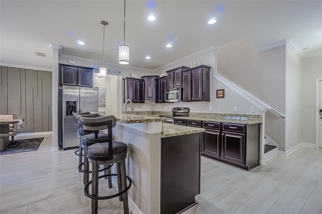 1762 Hadden Hall Place Trinity, FL 34655 - Photo 18 of 39 a kitchen with kitchen island granite countertop wooden cabinets and stainless steel appliances