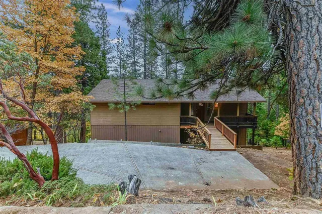 a view of a house with large trees and a wooden fence