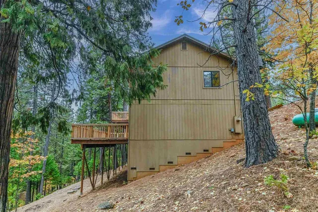 a view of a wooden house with large trees and wooden fence