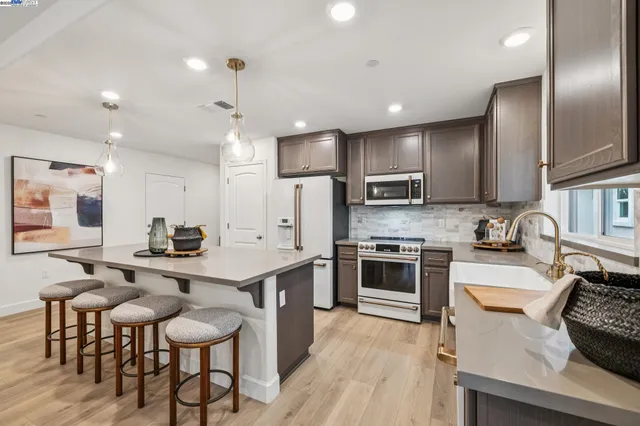 a kitchen with stainless steel appliances granite countertop a stove top oven a sink dishwasher a dining table and chairs with wooden floor