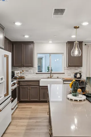 a large kitchen with stainless steel appliances granite countertop a stove a sink dishwasher and a refrigerator with wooden floor