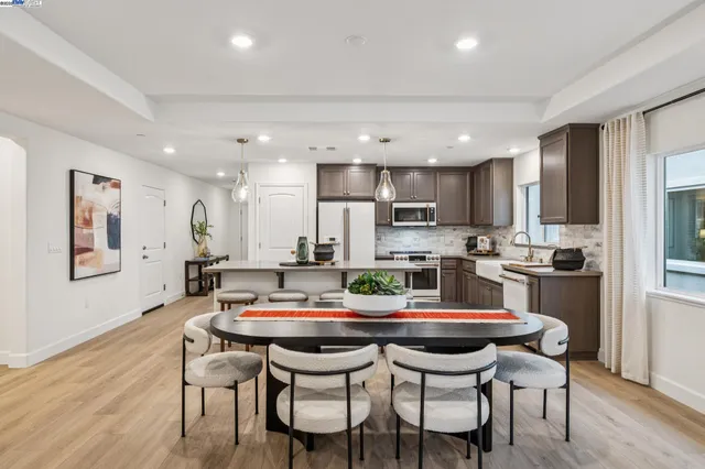 a kitchen with a dining table chairs and wooden floor
