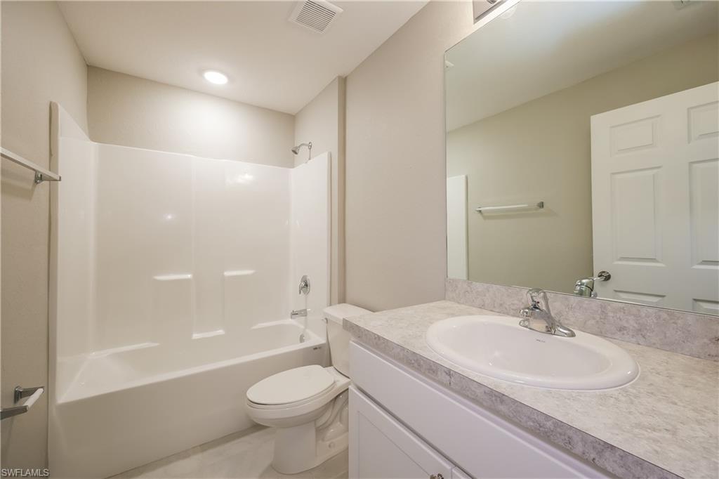 1218 Beaver Street East Lehigh Acres, FL 33974 - Photo 7 of 15 a bathroom with a sink a toilet and a large mirror