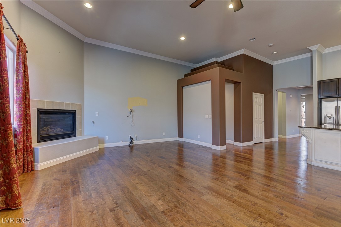 972 Rue Grand Paradis Lane Henderson, NV 89011 - Photo 10 of 32 Unfurnished living room featuring crown molding, light wood finished floors, a fireplace, ceiling fan, and recessed lighting
