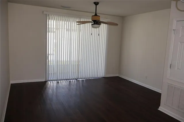 an empty room with wooden floor a ceiling fan and windows