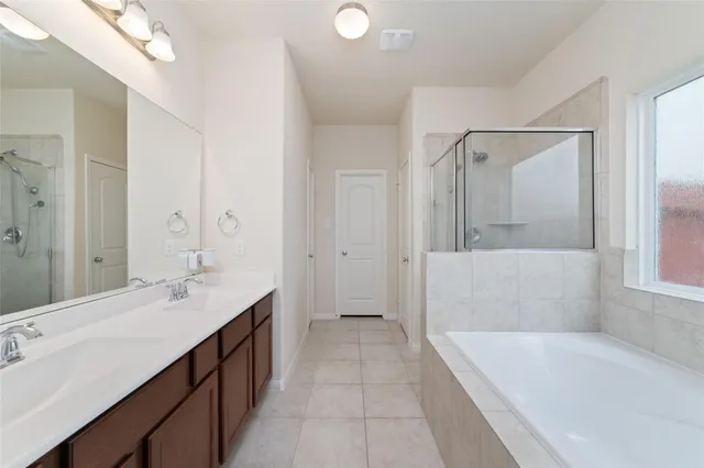 a spacious bathroom with a tub sink and mirror