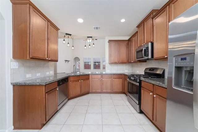 a kitchen with stainless steel appliances granite countertop wooden cabinets a stove top oven a sink and dishwasher