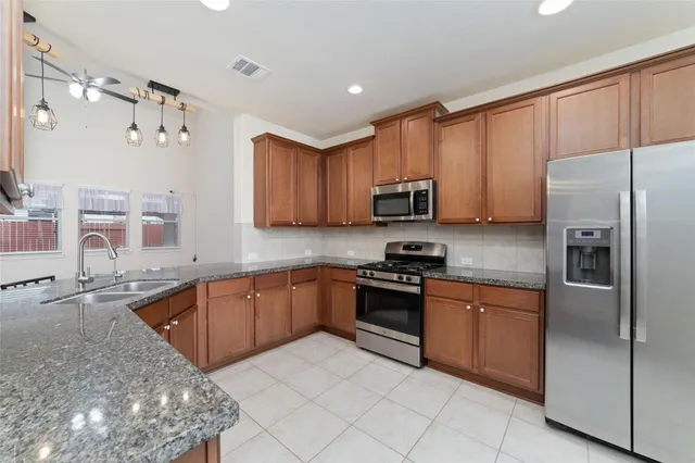 a kitchen with stainless steel appliances granite countertop a sink dishwasher stove top oven and refrigerator