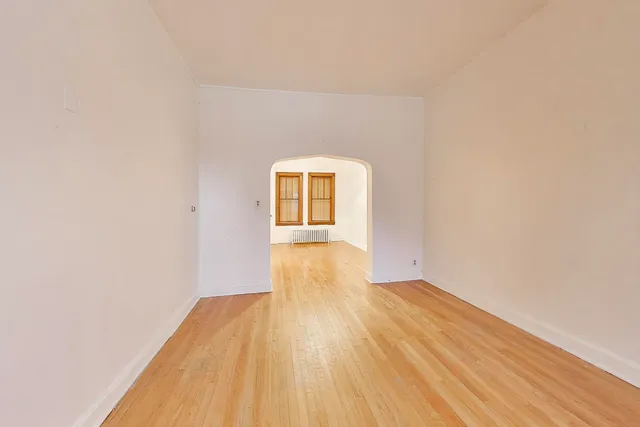 a view of a big room with wooden floor and windows