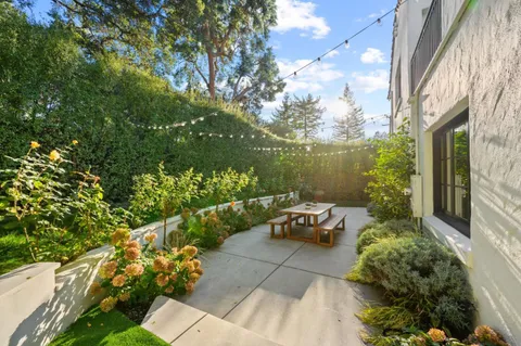 a view of a patio with couches table and chairs with plants and wooden fence