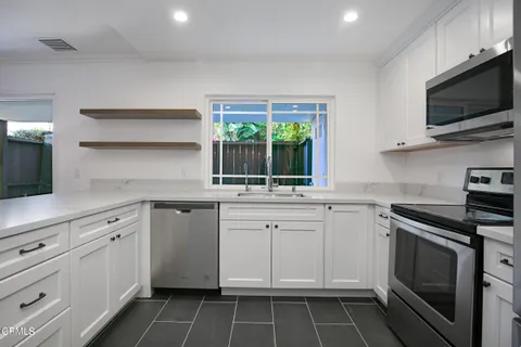 a kitchen with white cabinets appliances and a sink