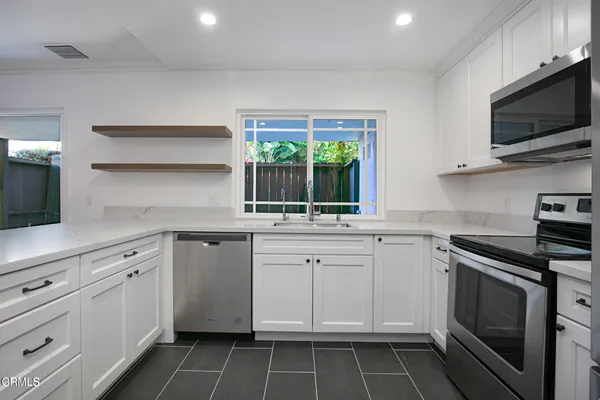 a kitchen with white cabinets appliances and a sink