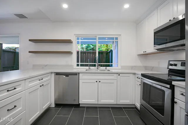 a kitchen with white cabinets appliances and a sink