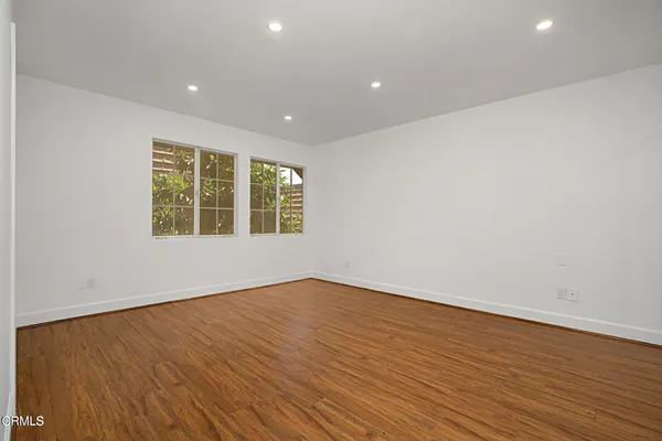 an empty room with wooden floor and windows