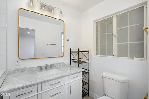 a bathroom with a granite countertop sink a toilet and a mirror