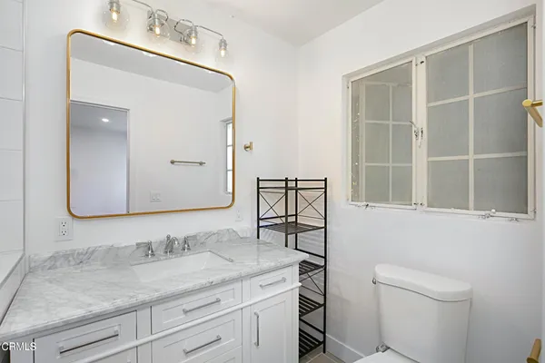 a bathroom with a granite countertop sink a toilet and a mirror