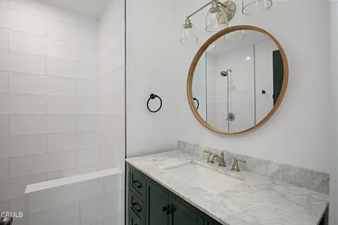 a bathroom with a granite countertop sink a mirror and shower