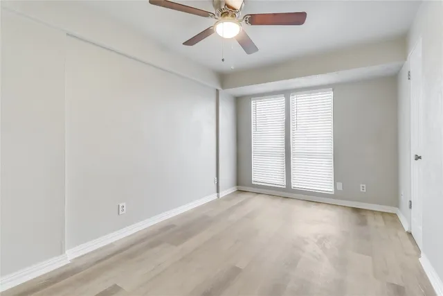 an empty room with chandelier fan and windows