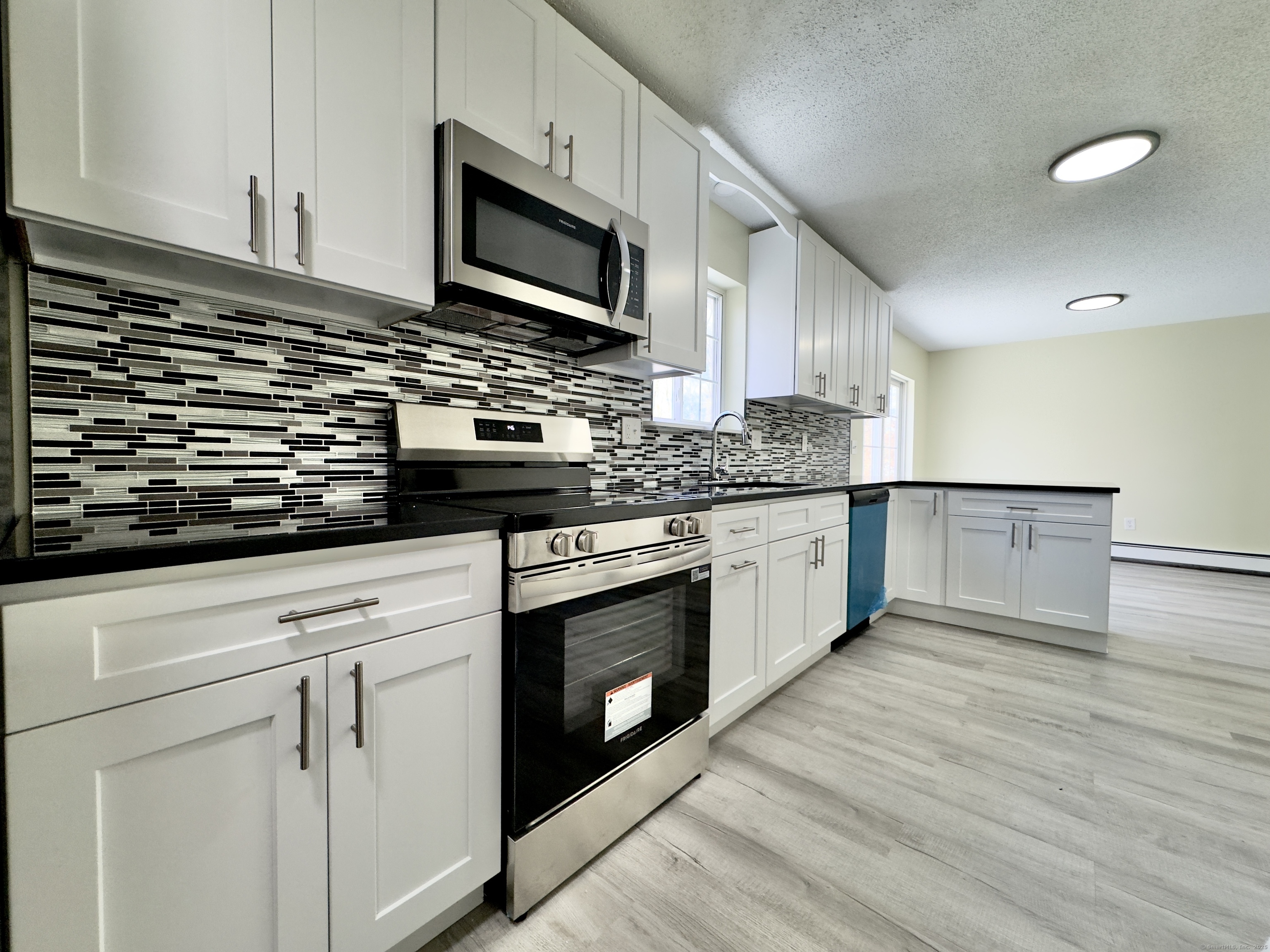 109 Winterberry Way Torrington, CT 06790 - Photo 6 of 22 a kitchen with stainless steel appliances granite countertop a sink a stove top oven and wooden floors