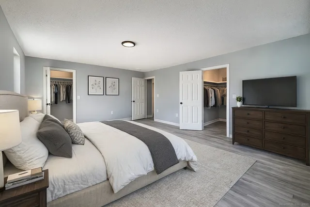 a spacious bedroom with a bed and a flat screen tv