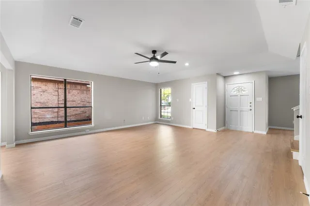 a view of an empty room with a window and a kitchen