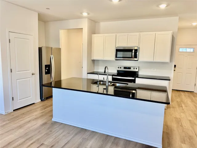 a kitchen with stainless steel appliances granite countertop a refrigerator and a stove top oven